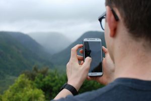 Un ragazzo intento a usare uno smartphone in montagna